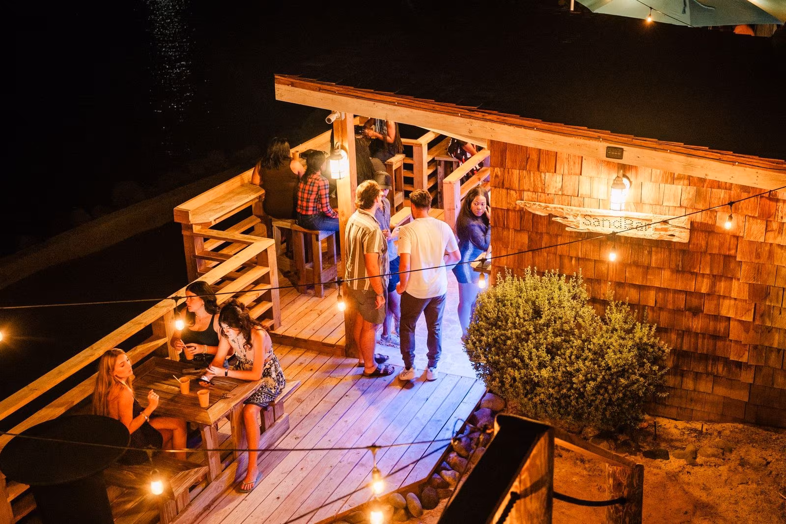 The SandBar at night — guests gathered on the deck under string lights